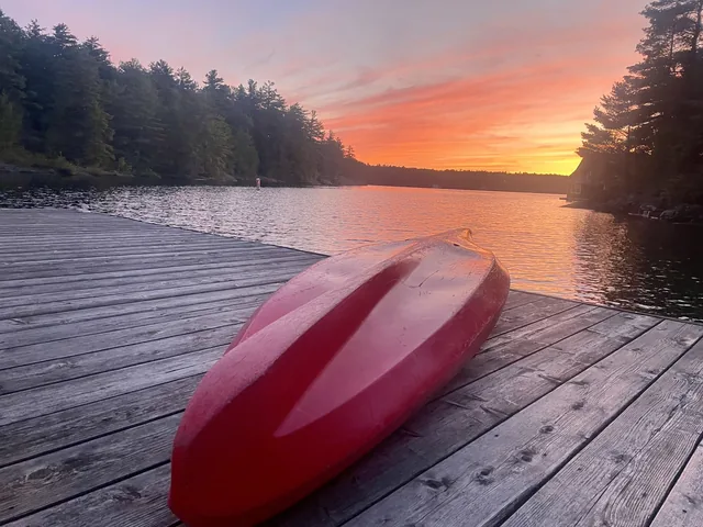 Sunset from the dock at Sterling Point, a red canoe on the boards and the sun low over the water